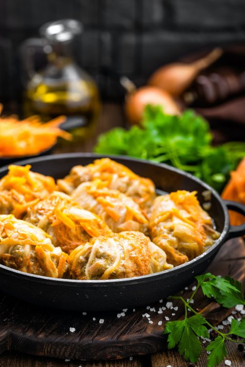 Cabbage rolls stewed with meat and vegetables in pan on dark wooden background Cabbage rolls stewed with meat and vegetables in pan on dark wooden background